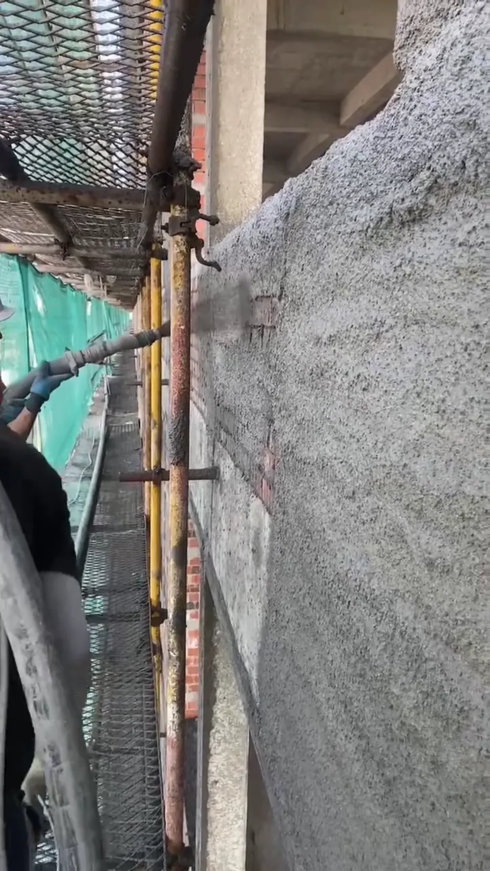 Worker spraying mortar onto a building wall
